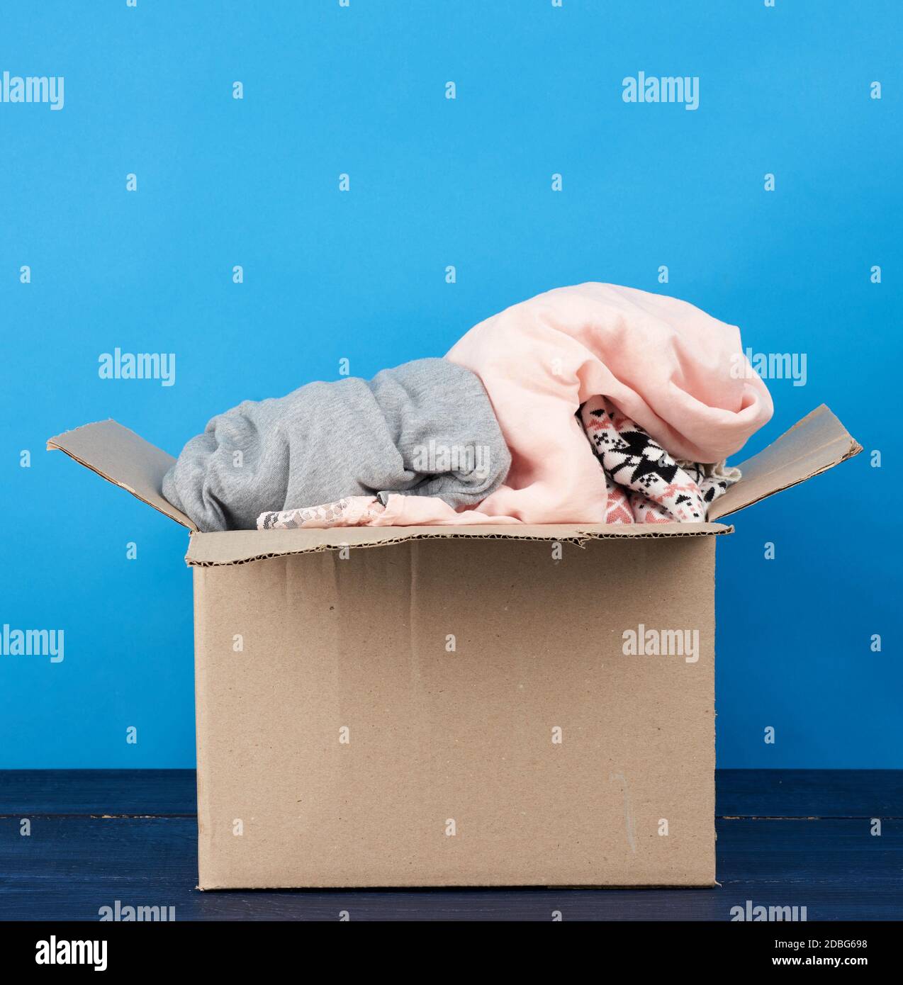 brown cardboard box full of various things on a blue wooden table ...