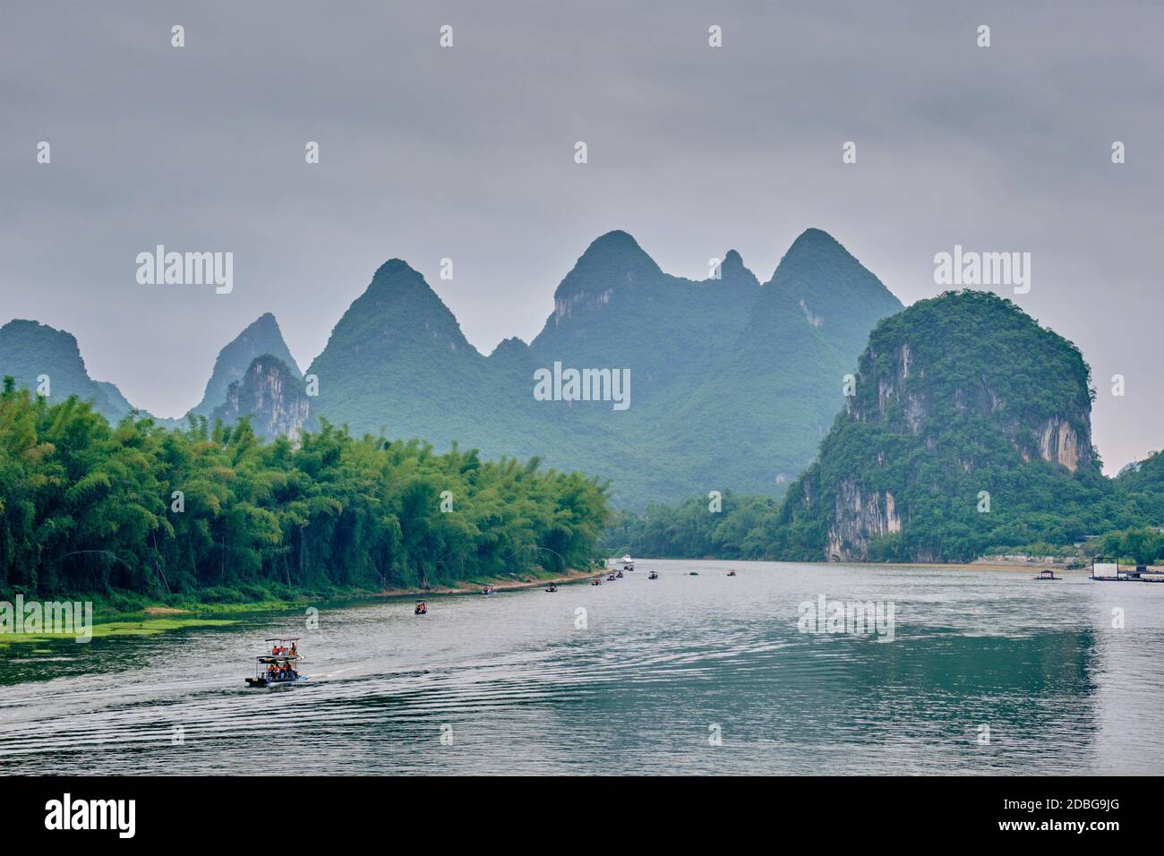 Tourist boats on Li river with dramatic karst mountain landscape in the background. Yangshuo, China Stock Photo