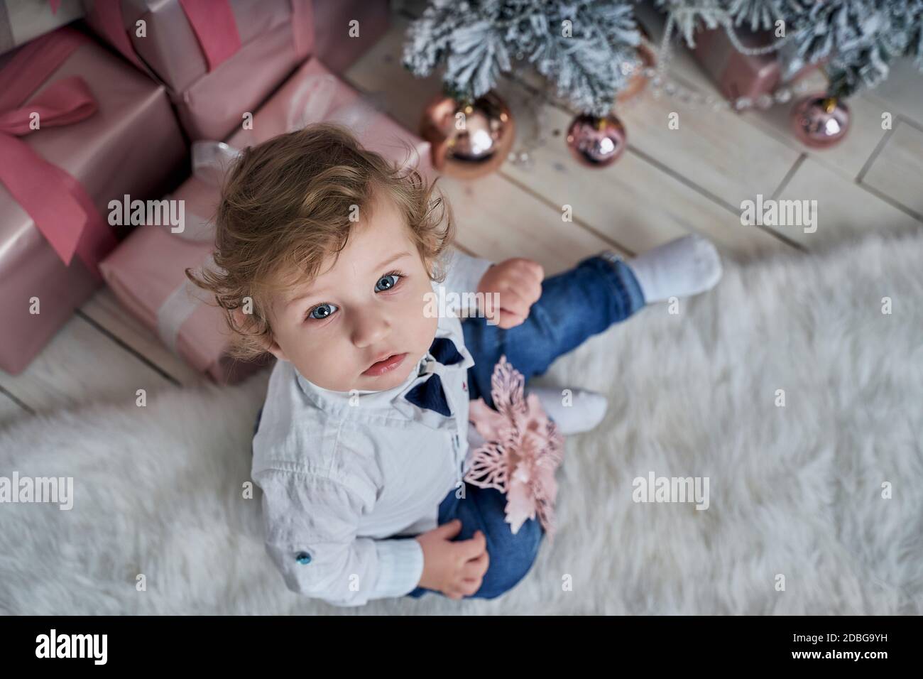 Little funny baby next to the Christmas tree. Stock Photo