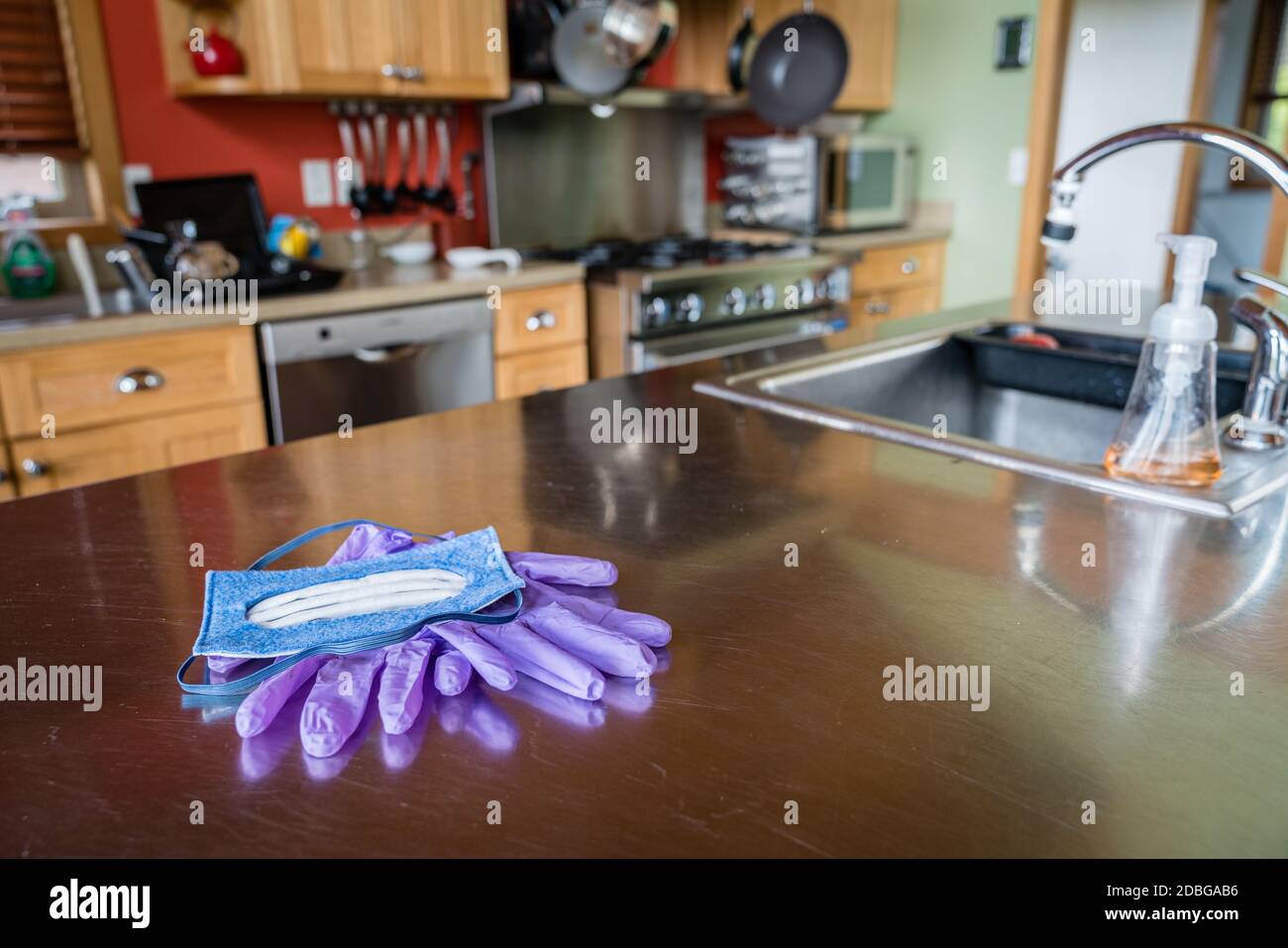 N-95 mask and nitrile disposable gloves on a steel kitchen table Stock Photo