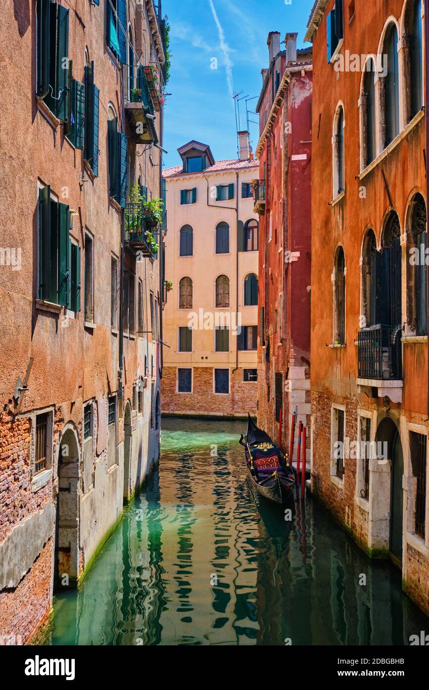 Narrow canal between colorful old houses with gondola boat in Venice ...