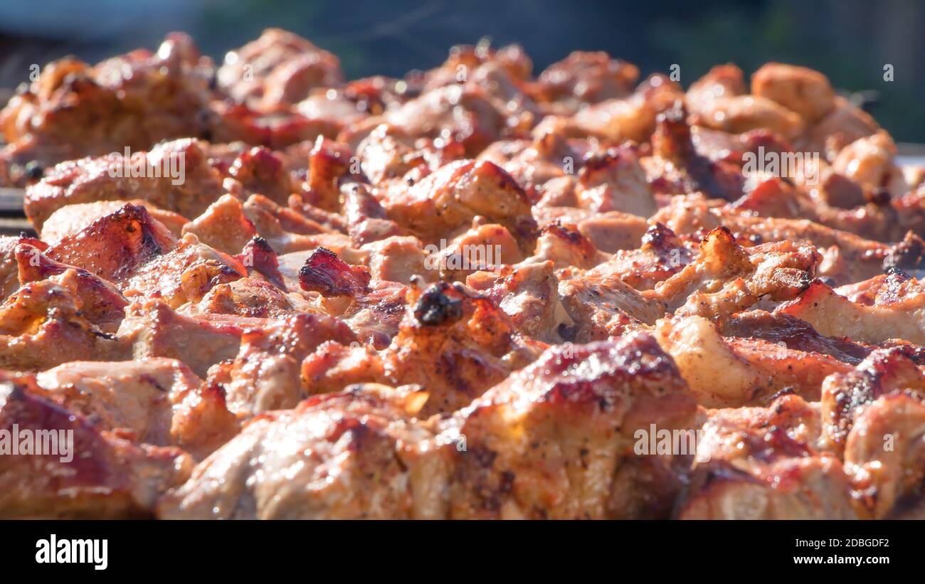 Fresh meat dressed on skewers is fried on a roaster or grill. The chef prepares meat in a cafe