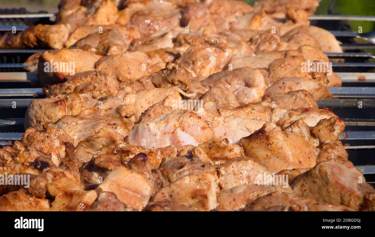 Fresh meat dressed on skewers is fried on a roaster or grill. The chef prepares meat in a cafe