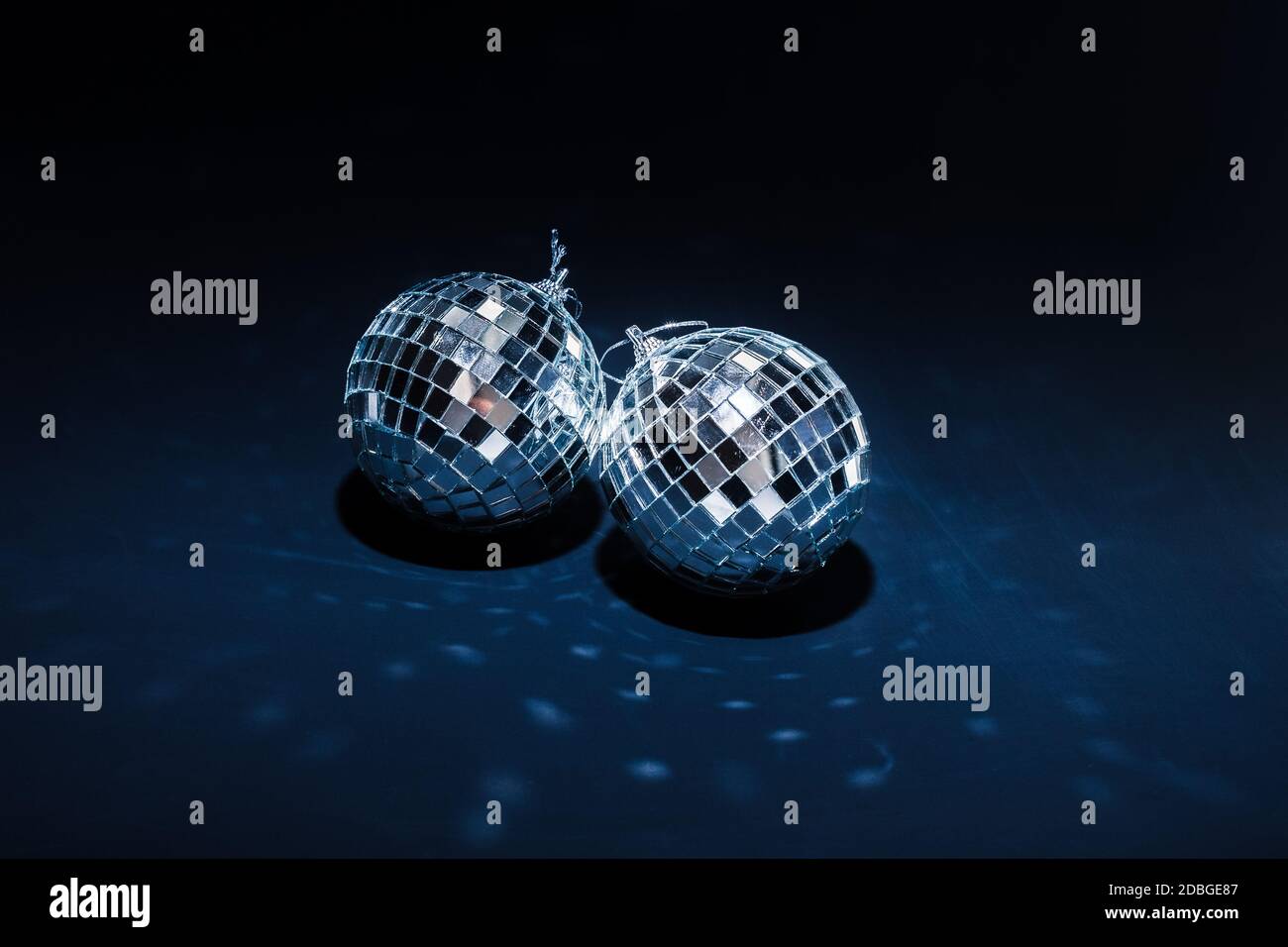 two mirror balls illuminated by bright light lie on dark blue