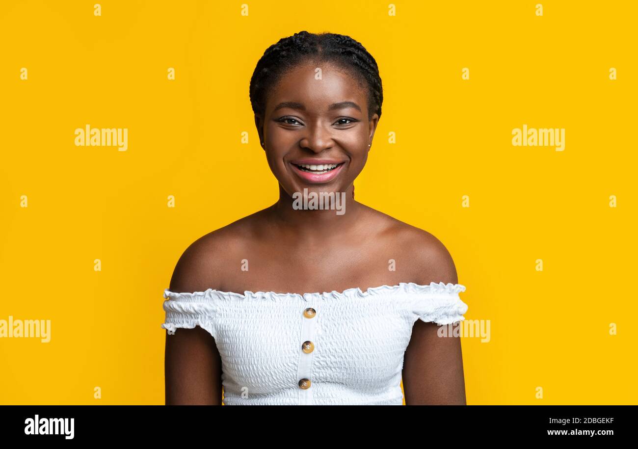 Portrait of young smiling african american woman with braids over yellow background Stock Photo