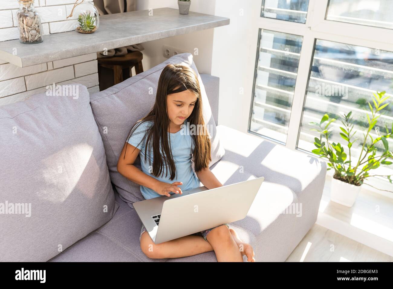 Little girl studying online using her laptop at home Stock Photo - Alamy