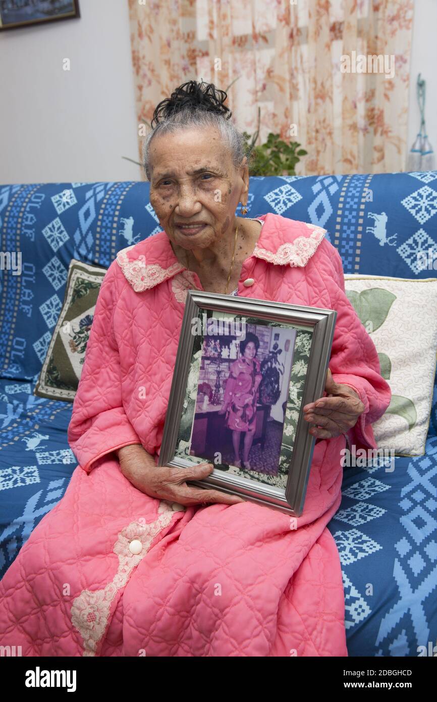 Portrait of a 0ne hundred and one year old woman holding a sixty year old photo of herself in New York City. Stock Photo