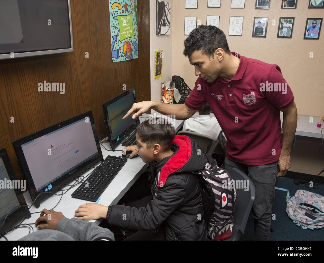 High school  age staff member helps a child on the computer at a community center after school on the Lower East Side, Manhattan, New York City. Stock Photo