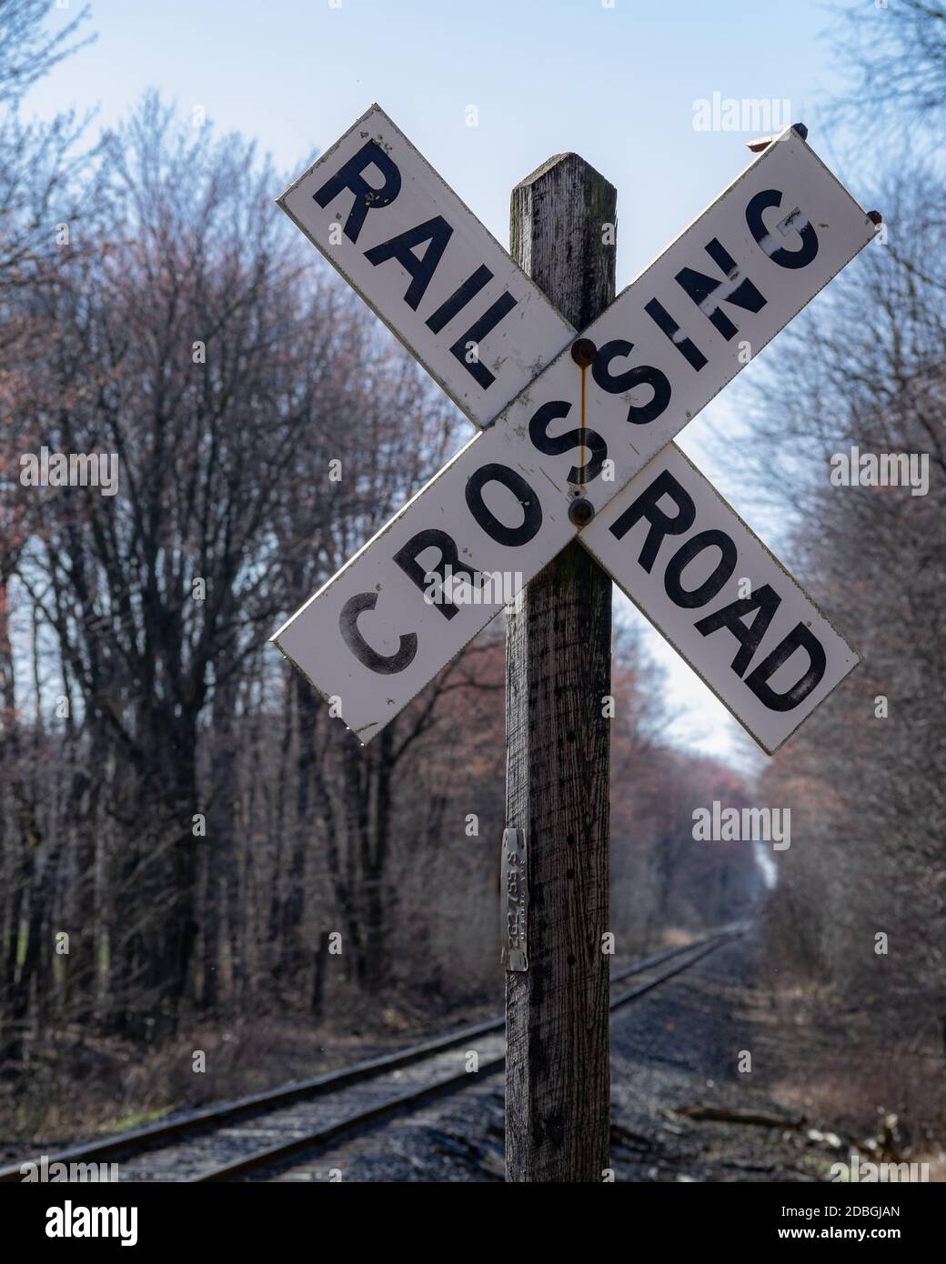 X shaped railroad crossing sign with tracks disappearing into distance