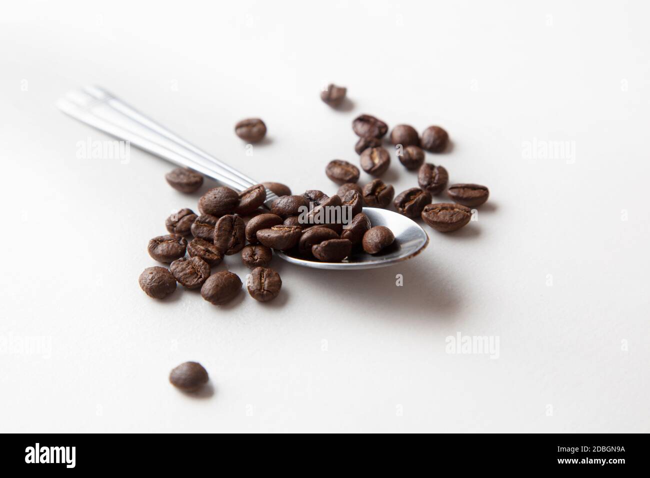 Spoon with coffee beans, macro photo. Isolated on white background Stock Photo