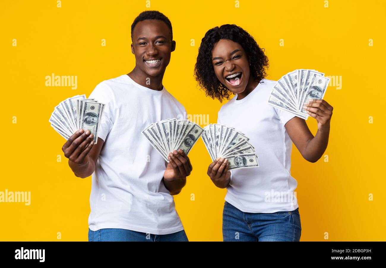Joyful black couple won lottery, showing prize at camera, screaming Stock Photo