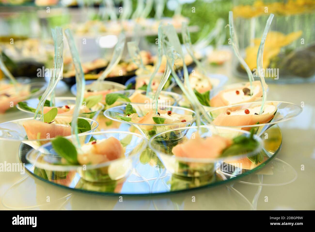 Buffet table with a display of salmon seafood appetizers on circular mirrors in a low angle shallow dof view at a catered event or wedding reception Stock Photo