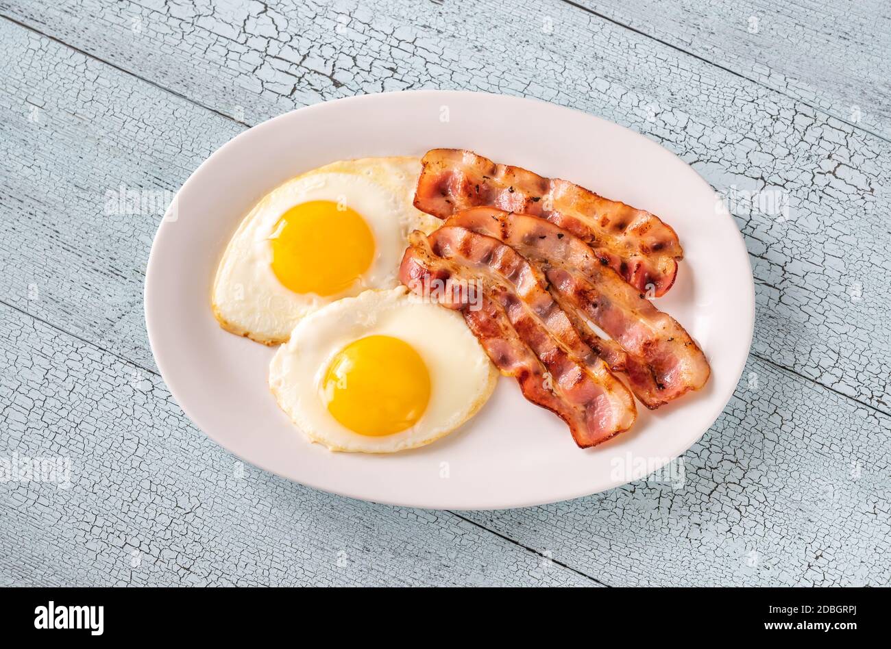 Fried eggs with strips of bacon on the white plate Stock Photo