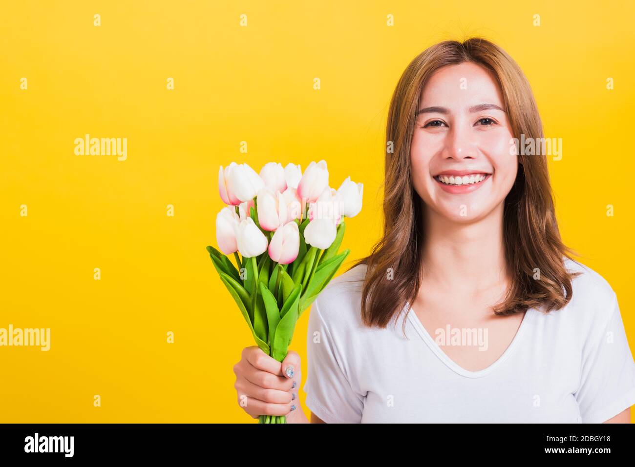 Portrait Asian Thai beautiful happy young woman smiling, screaming excited hold flowers tulips bouquet in hands and looking to camera, studio shot iso Stock Photo
