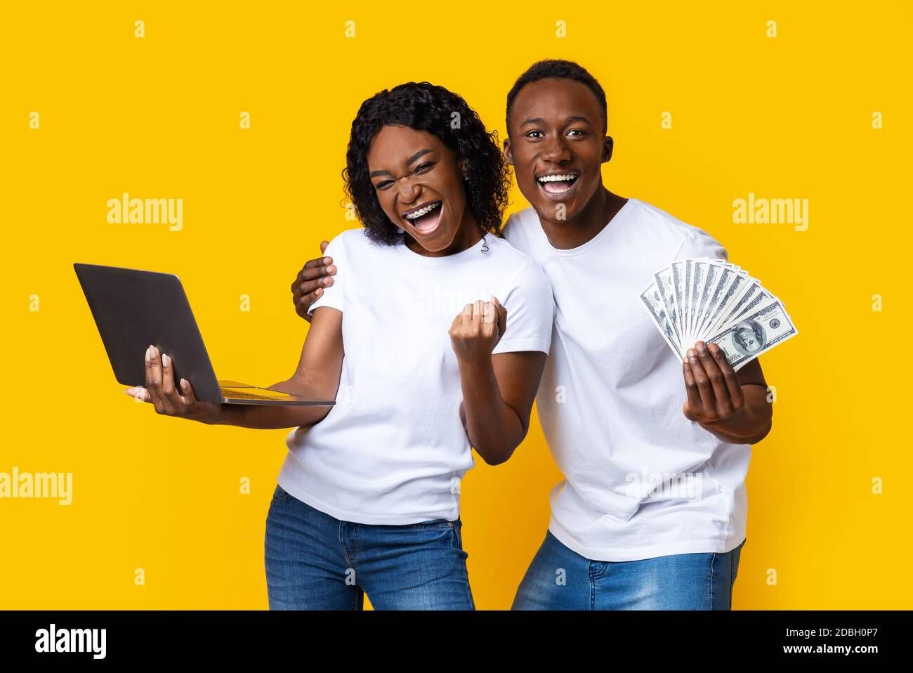 Happy black couple celebrating win with laptop and cash Stock Photo - Alamy