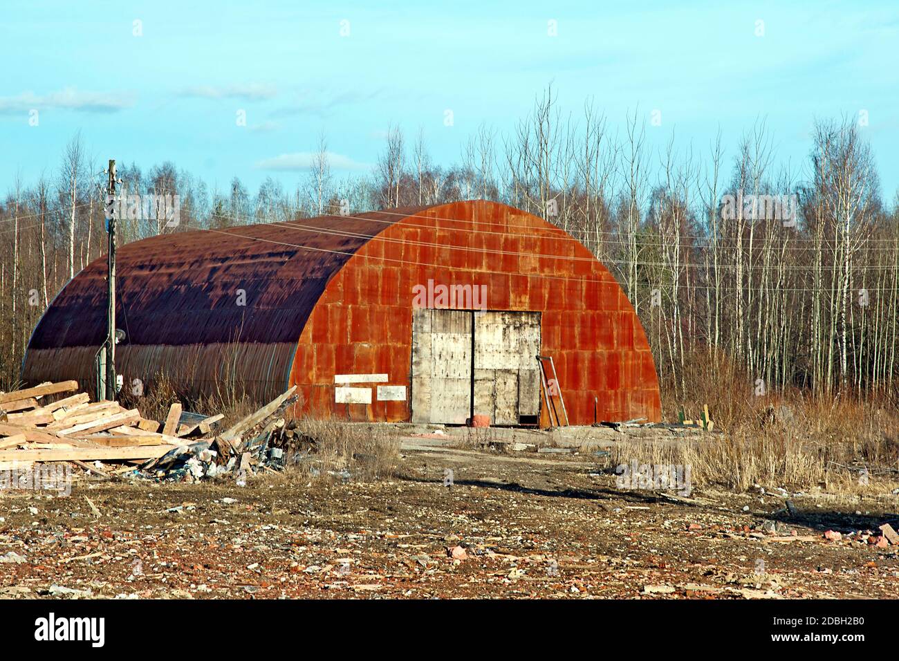 View of an old, rusty, abandoned hangar. An image of decrepitude or a natural disaster. Stock Photo