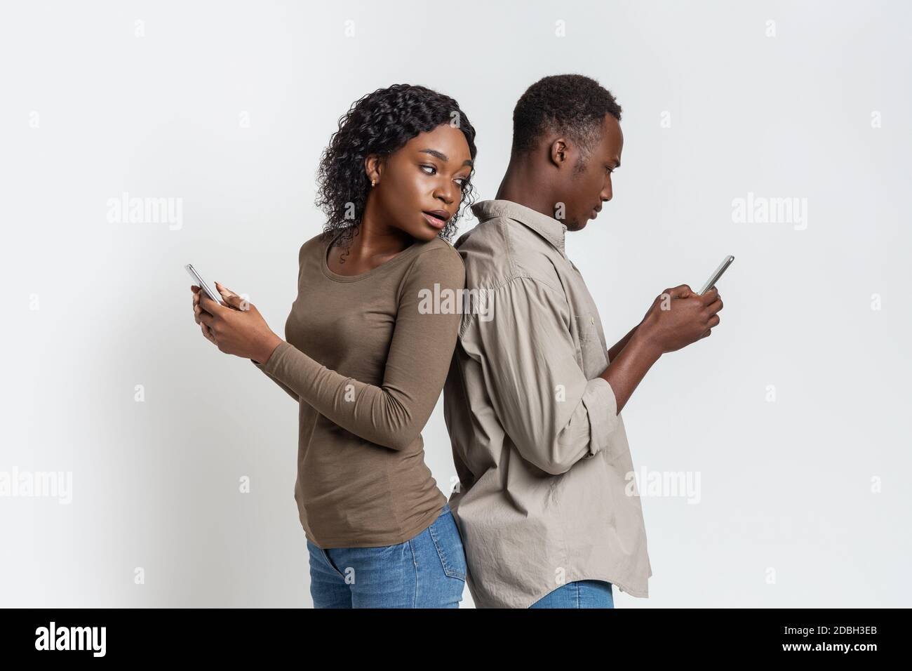 Black couple standing back to back, using smartphones Stock Photo