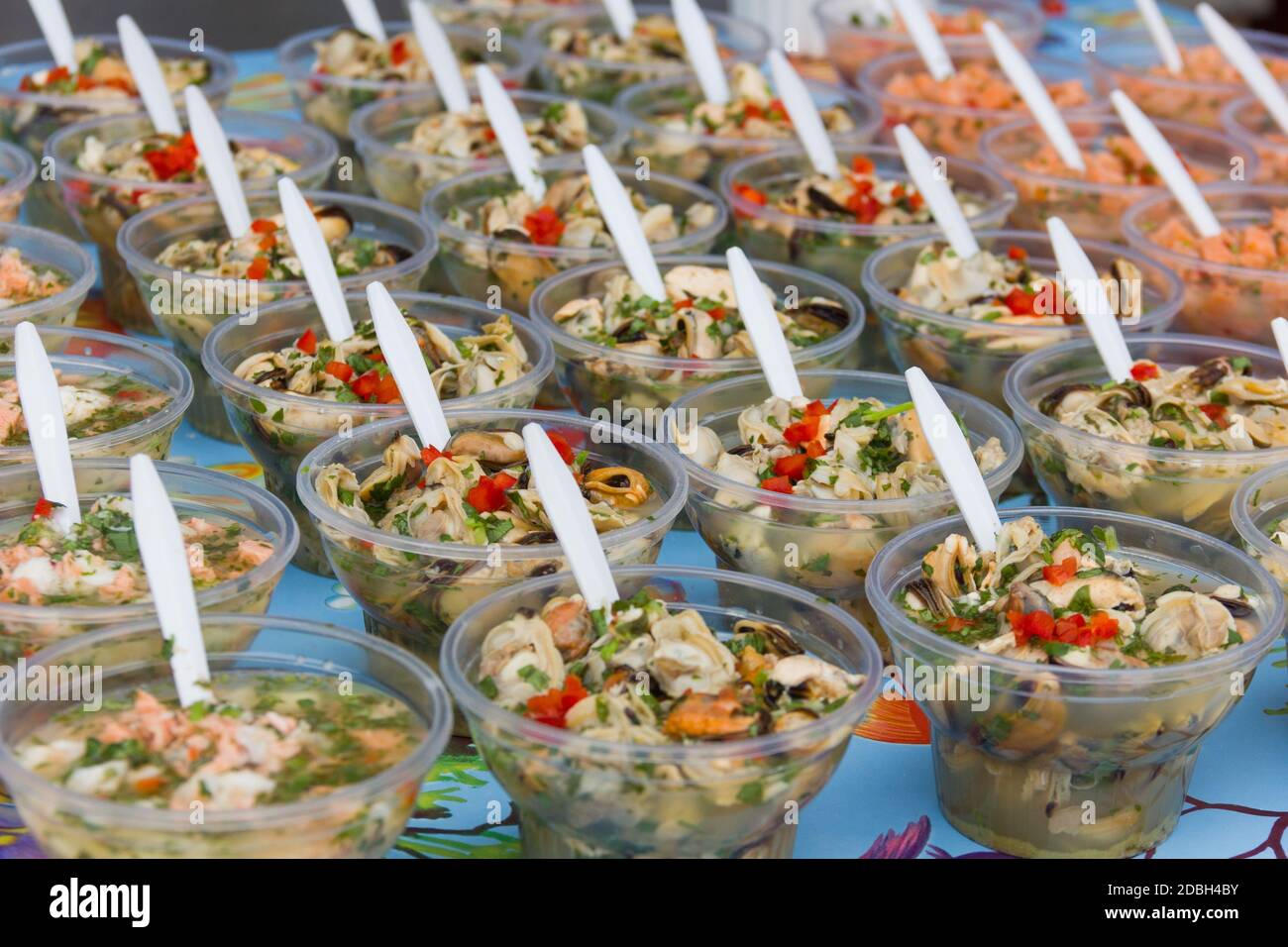 Display of different variety of ceviche in plastic glasses perfectly lined up with white spoons at Angelmo Bay market in Puerto Montt, Chile Stock Photo