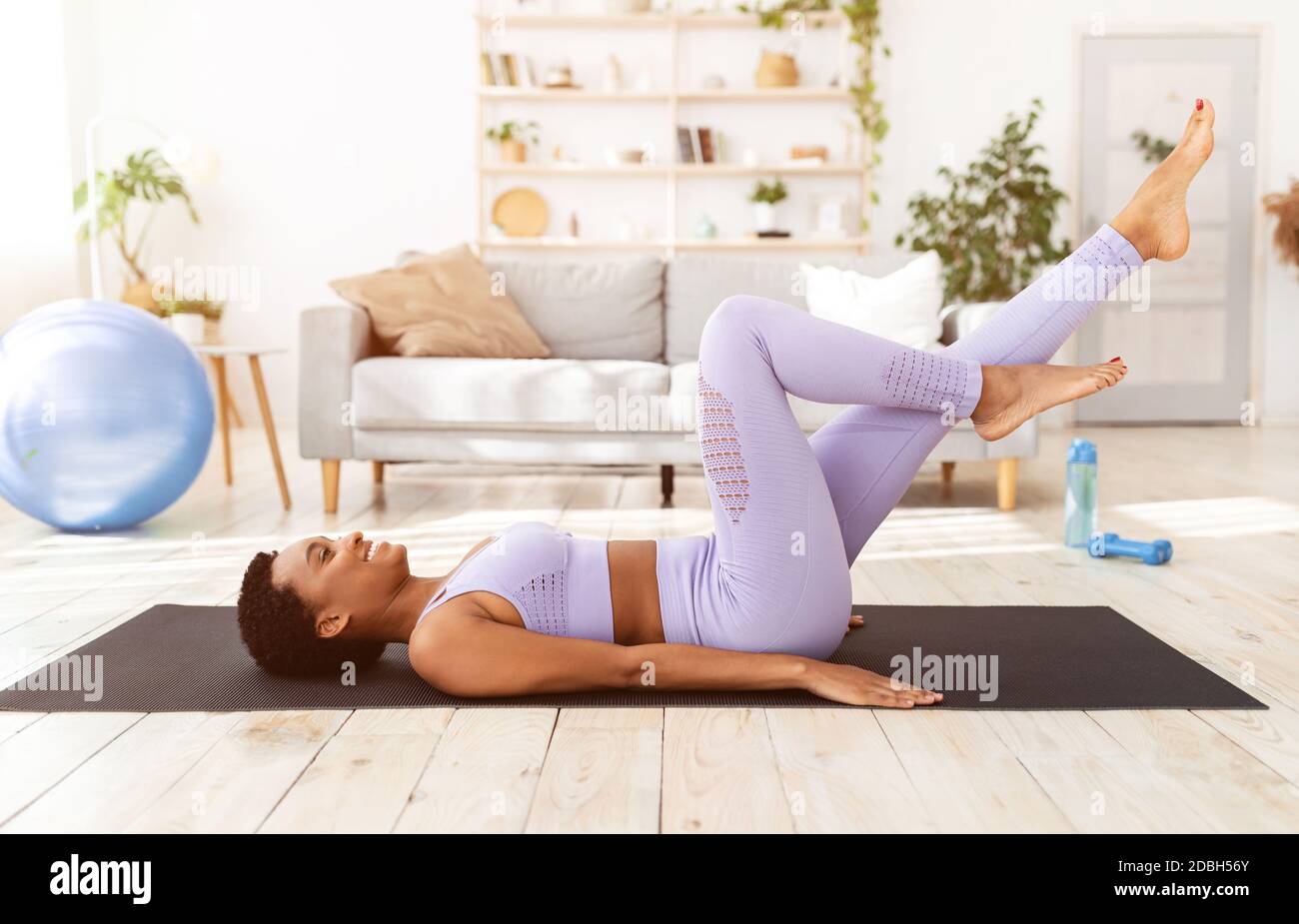 Home workout during covid-19 lockdown. Fit black woman doing air cycling  exercise on yoga mat at home Stock Photo - Alamy