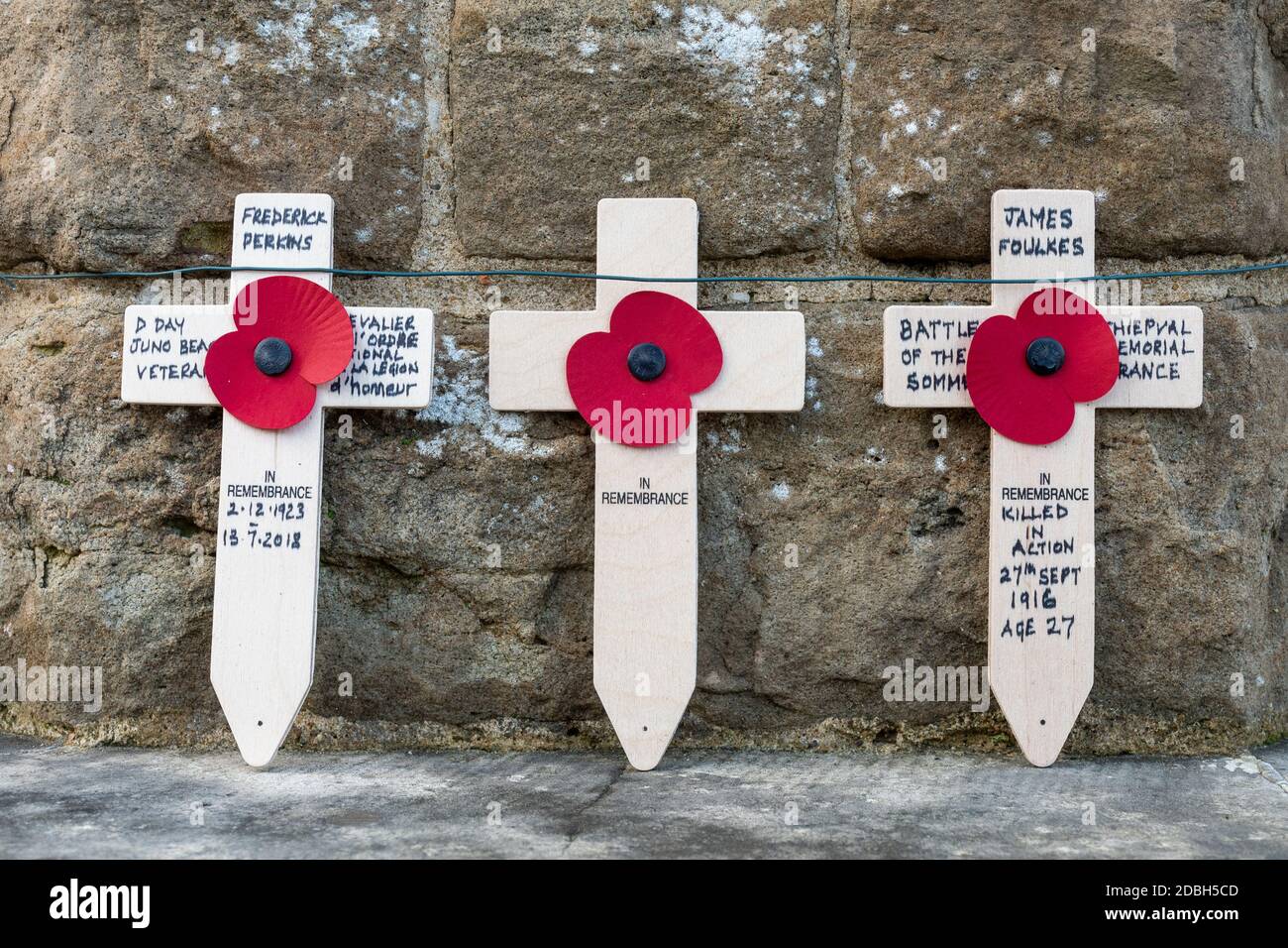 Three poppy crosses placed around a war memorial to commemorate remembrance day or armistice, UK Stock Photo