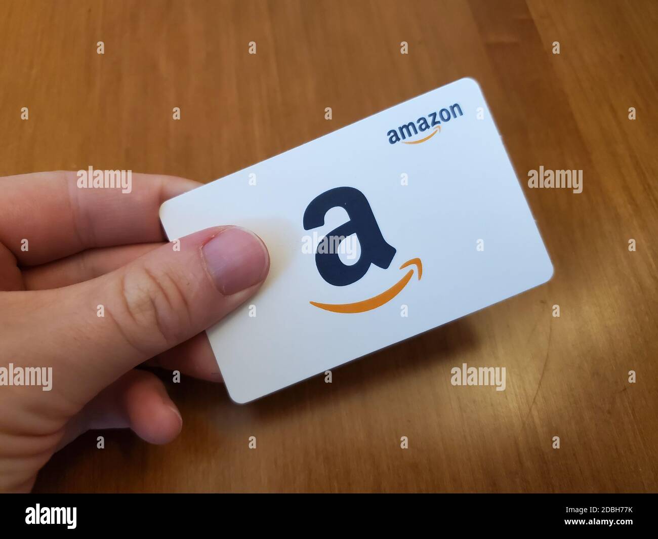 Person holding a white Amazon gift card featuring the