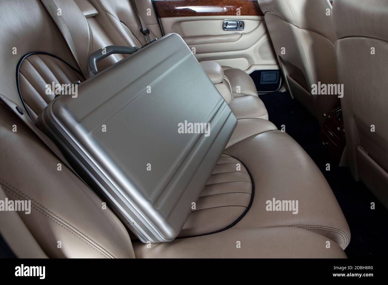 Luxury metal briefcase on the car back seat. Creme leather Stock Photo