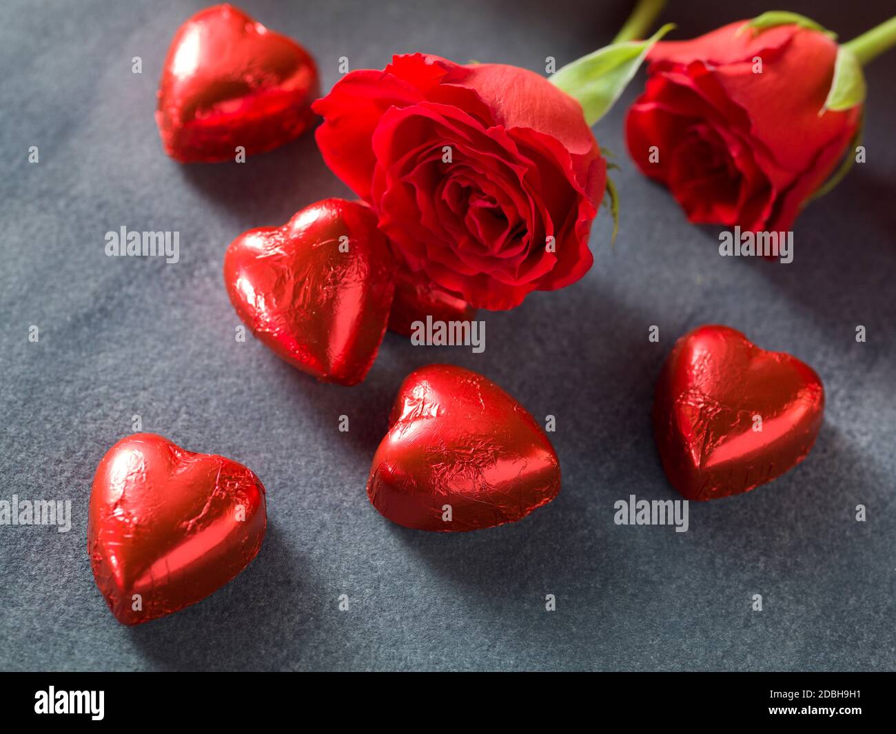 Red roses with chocolate hearts on a grey background. Valentines day ...