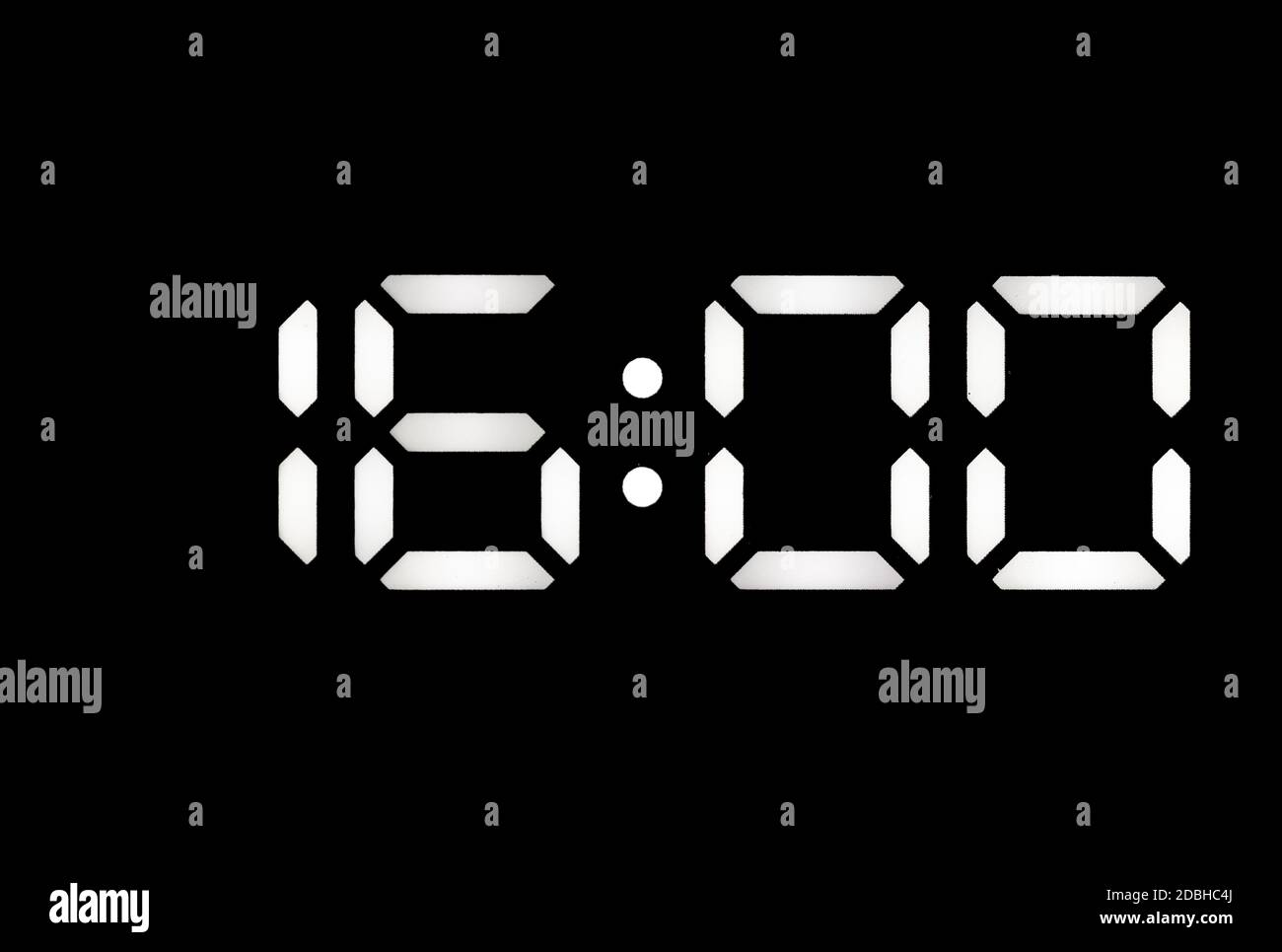 Real white led digital clock on a black background showing time 16:00 Stock Photo