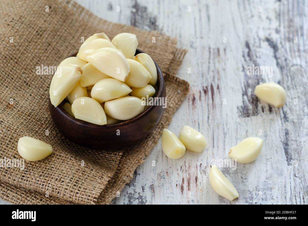 Peeled fresh garlic in the wooden bowl on kitchen table Stock Photo - Alamy