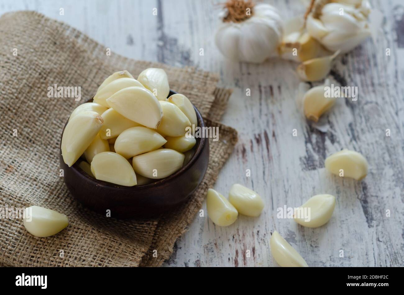 Peeled fresh garlic in the wooden bowl on kitchen table Stock Photo - Alamy