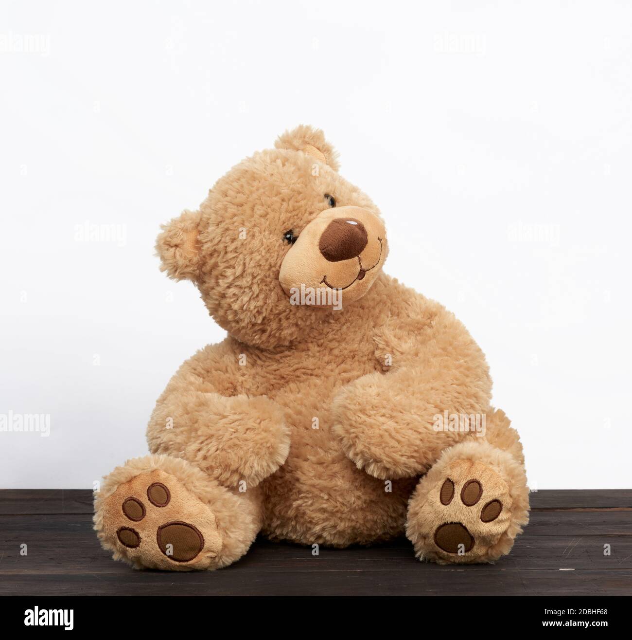 brown teddy bear sits on a brown wooden table, white background Stock ...
