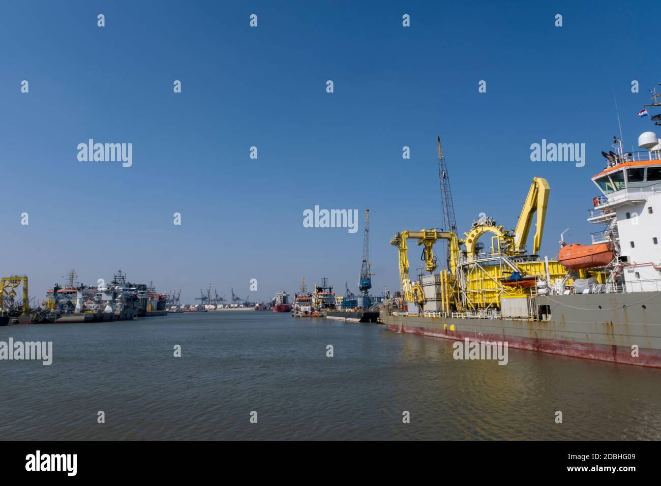 Huge cranes and ships anchored at harbor. International commercial port, city of Rotterdam background. Logistics business Stock Photo