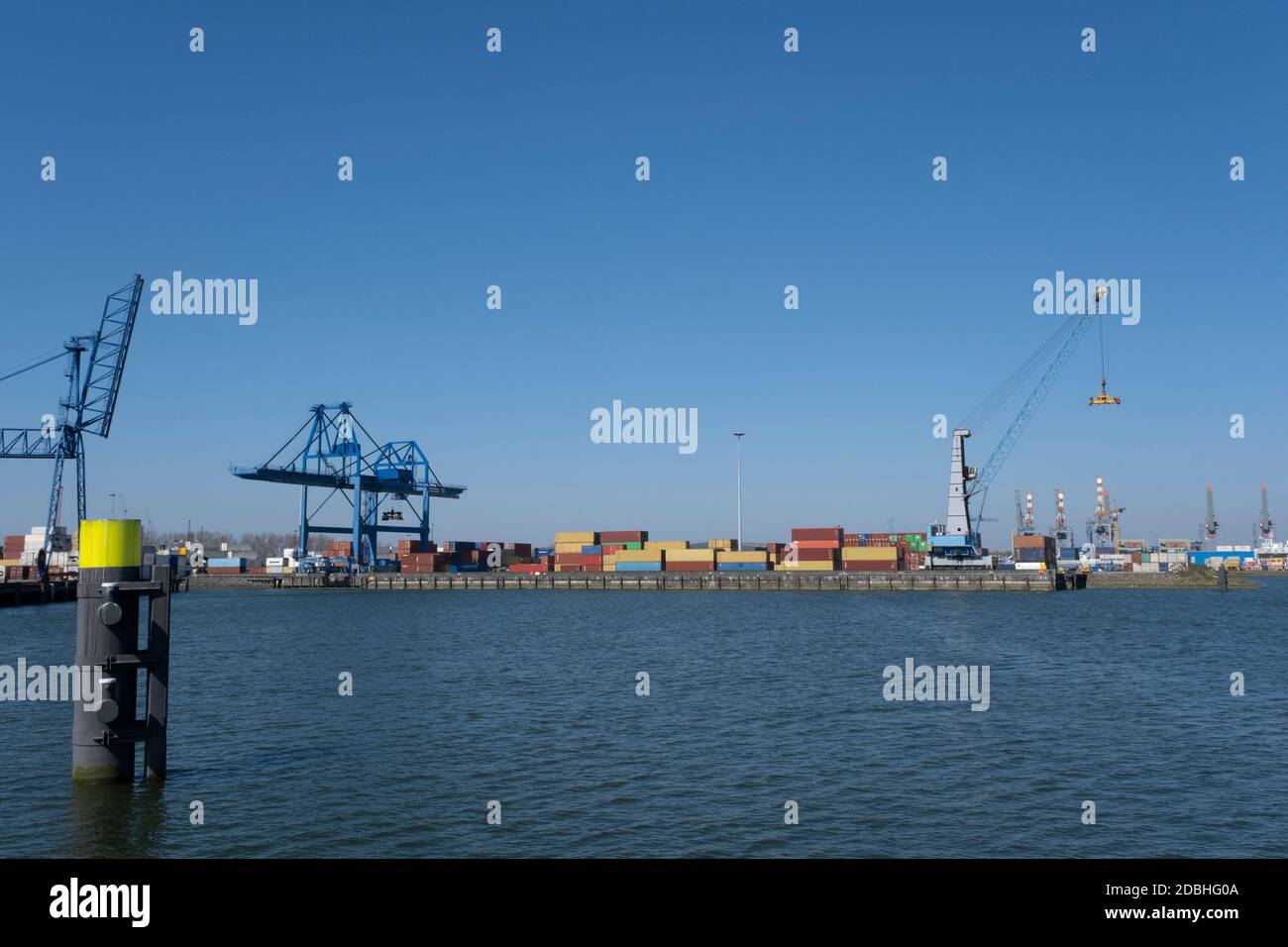 Huge cranes and ships anchored at harbor. International commercial port, city of Rotterdam background. Logistics business Stock Photo