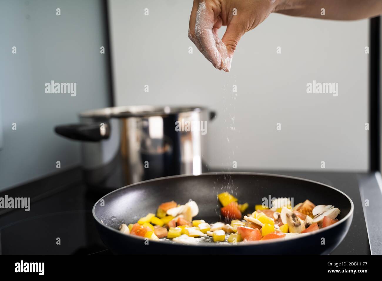 Woman Cooking At Home In Kitchen Adding Salt Stock Photo Alamy