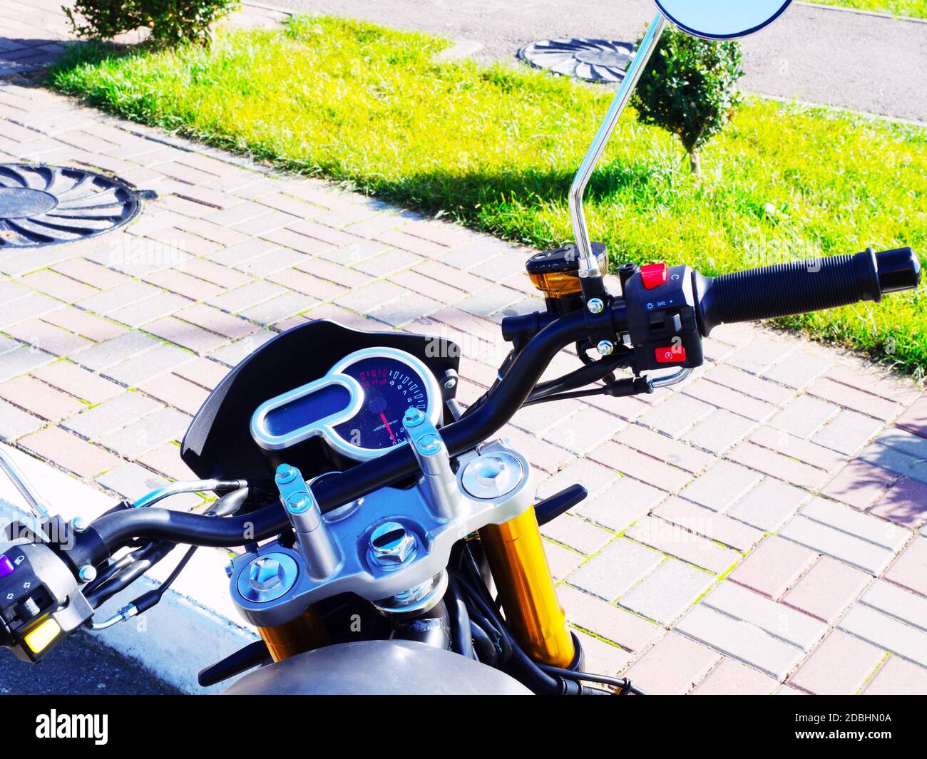 The steering wheel of a motorcycle is standing on the sidewalk on a sunny day Stock Photo