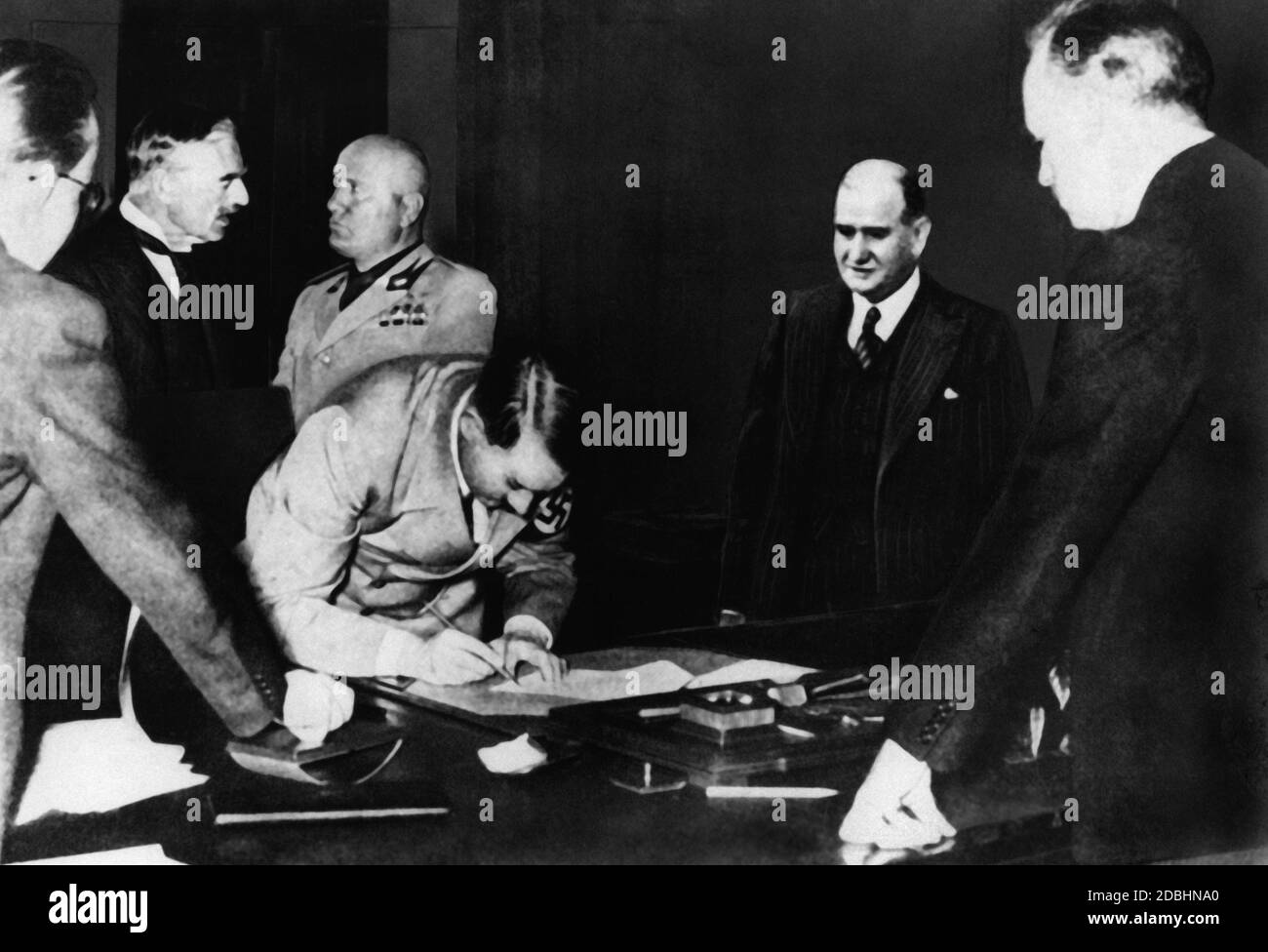 Adolf Hitler signing the Munich Agreement. In the background Chamberlain and Benito Mussolini. On the right, Daladier and Ribbentrop. Stock Photo