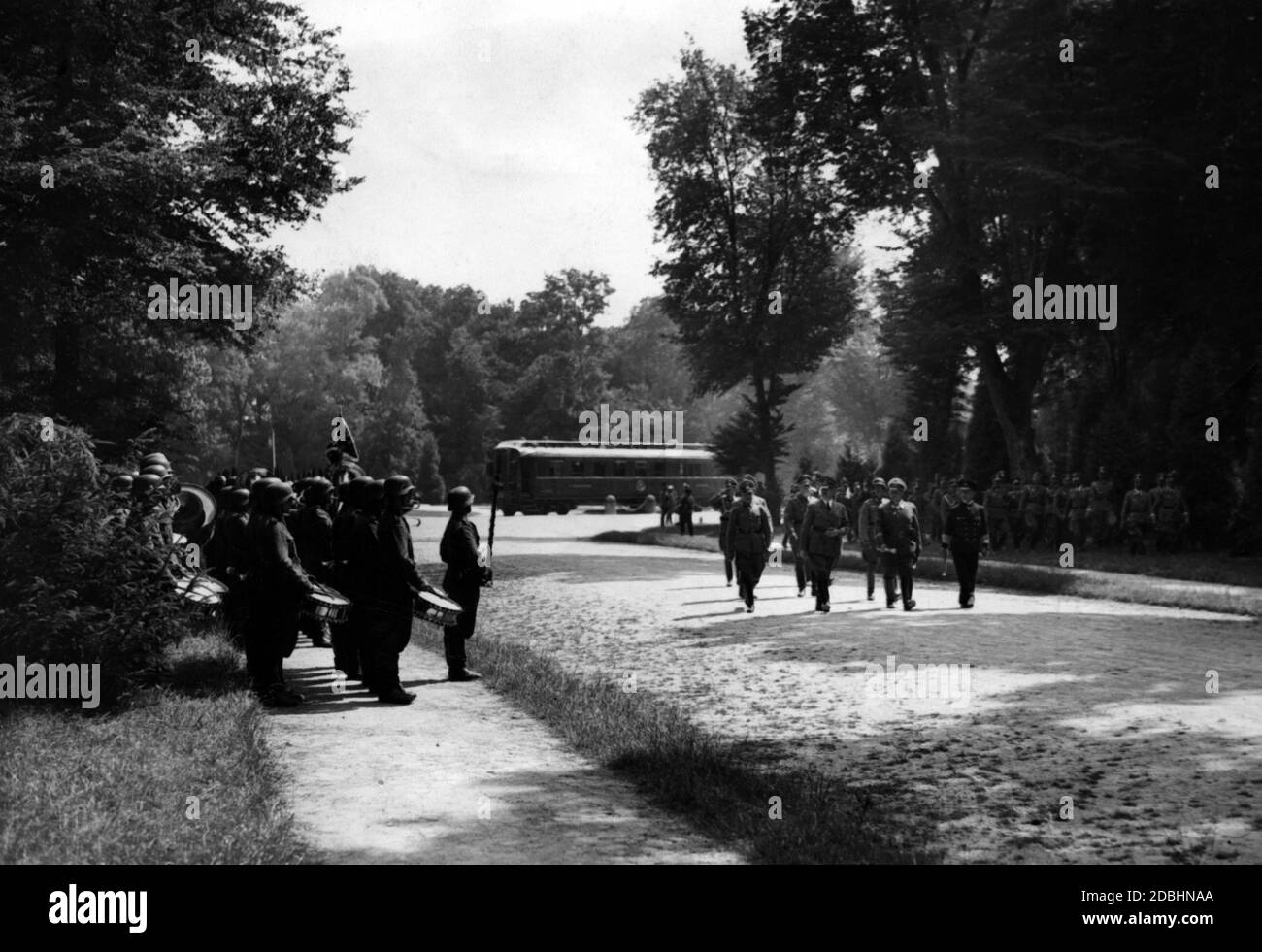 Hitler and his commanders-in-chief of the Luftwaffe and the Navy inspect an honor guard of the Wehrmacht in the forest of Compiegne. In the background, the Compiegne wagon in which was signed the peace treaty in 1918, which was considered disgraceful by the Nazis. The following day, it served Hitler's revenge as a renewed site for the signing of peace terms - this time according to German dictates. Werner von Brauchitsch and Wilhelm Keitel are barely recognizable in the second row. Stock Photo