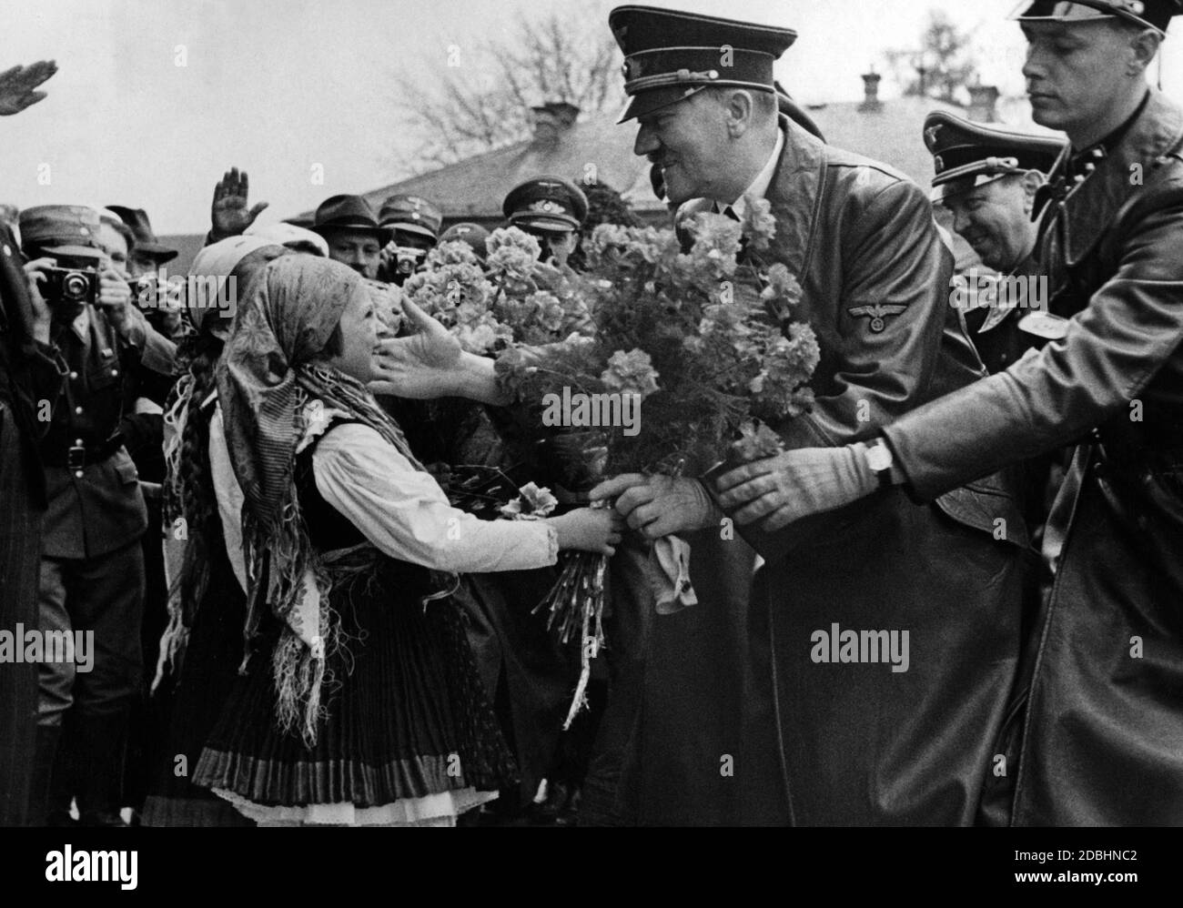 Adolf Hitler pats the cheek of a little girl who presents him with a bouquet of flowers. Behind Hitler Julius Schaub. Maribor - German-Austrian Marburg an der Drau - was an essentially German-speaking city in Austria-Hungary until 1918. Stock Photo