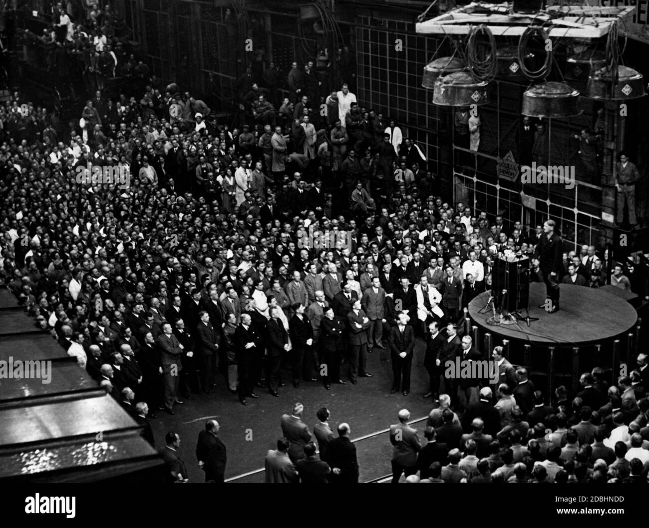 Adolf Hitler gives a speech in a machine hall of the Siemens-Schuckertwerke dynamo factory, which was broadcast throughout Germany during the lunch break. Stock Photo