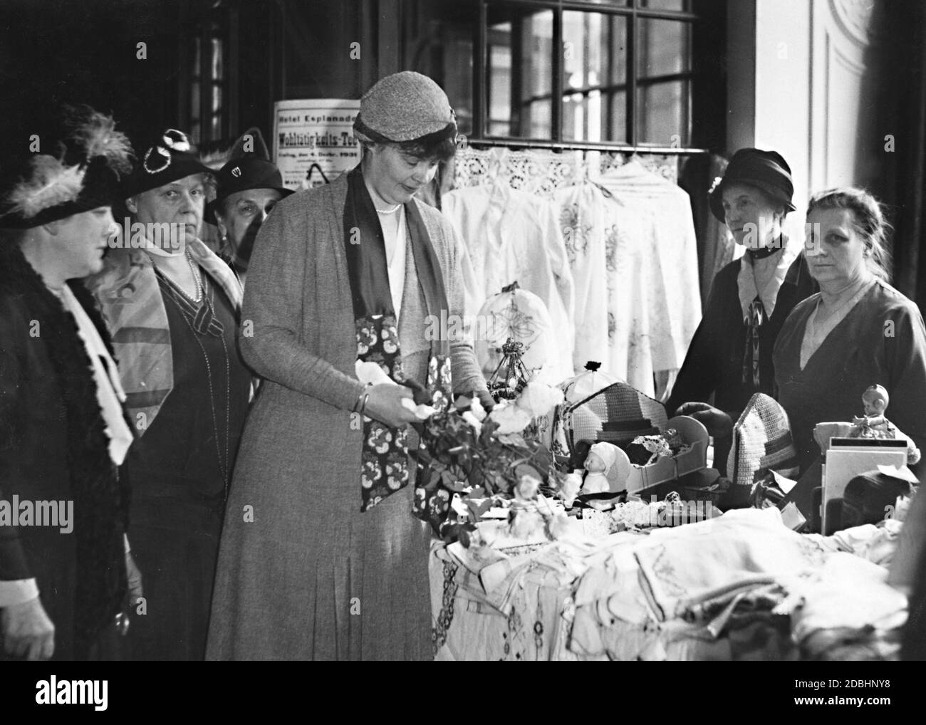 'Crown Princess Cecilie shops at the Christmas charity bazar in the Grand Hotel Esplanade in Berlin in 1931. The proceeds of the goods sold (including many artistic handicrafts) are donated to the Winterhilfe. The Christmas mass was organized by the Deutsche Adelsgenossenschaft. In the background hangs a poster advertising a ''Charity Tea'' in the Hotel Esplanade.' Stock Photo