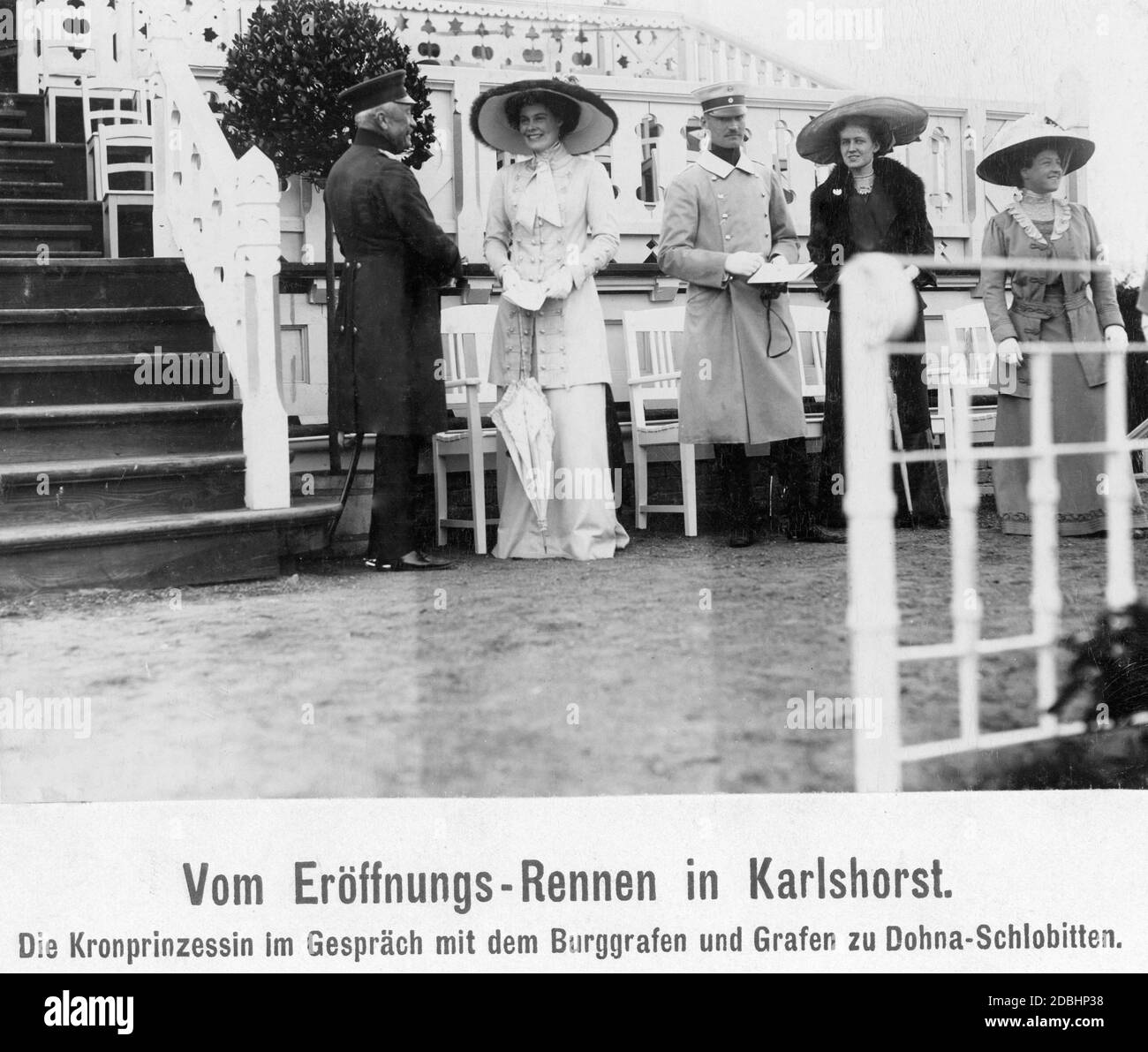 Alfred Graf and Burggraf zu Dohna-Schlobitten (left) talking to Crown Princess Cecilie of Mecklenburg (right). They are standing in front of the grandstand of the trotting track in Karlshorst in Berlin, waiting for the opening race in 1911. Stock Photo
