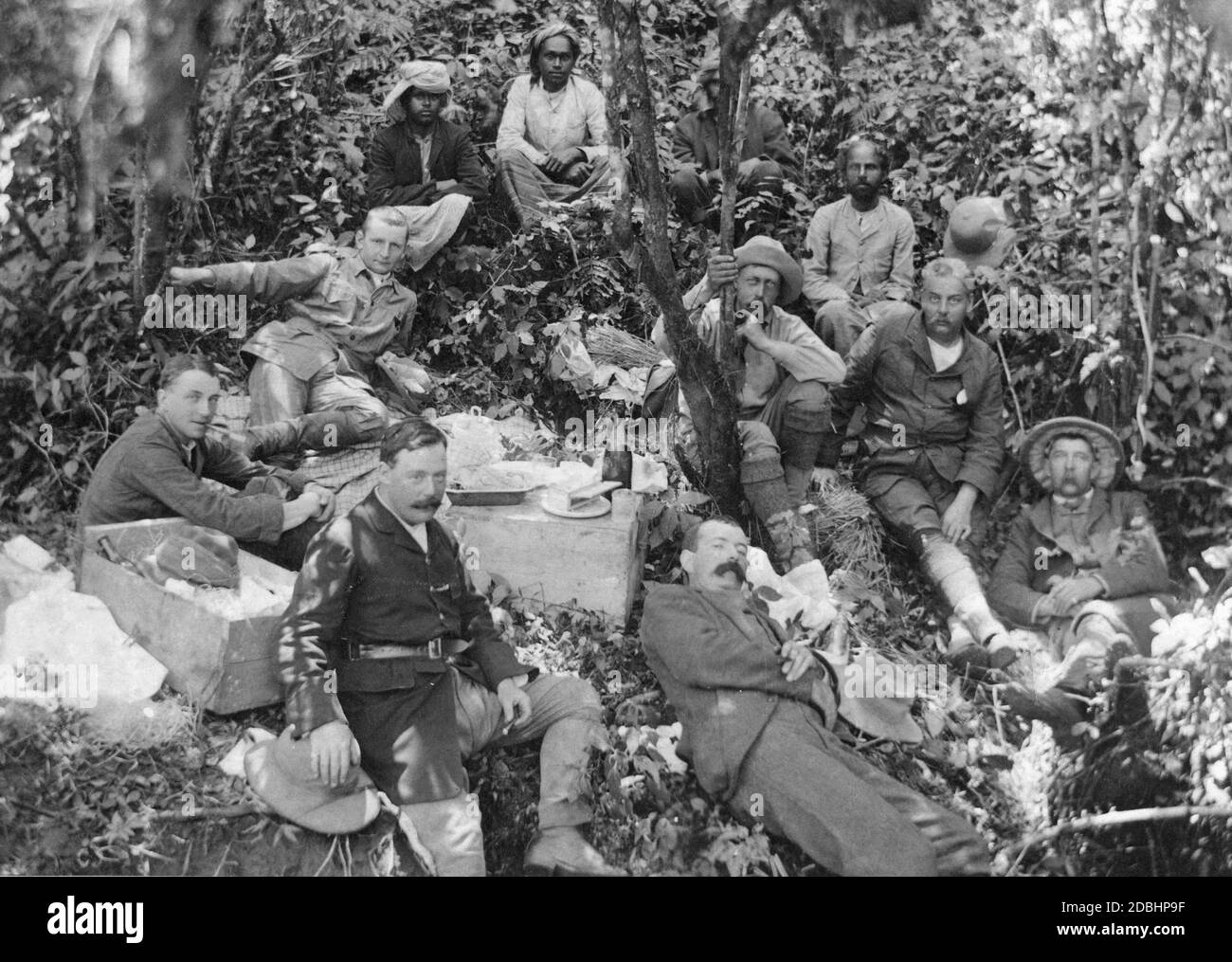 Prince Henry of Prussia (centre, holding on to a tree and smoking a pipe) is on a hunting trip in Nuwara Eliya in Sri Lanka. The hunting party is taking a break with food and drink. The picture was probably taken in the 1890s. Stock Photo
