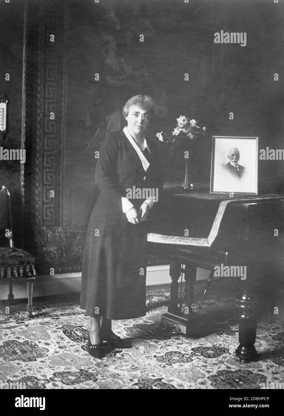 The photograph shows Hermine Reuss Elder Line, the second wife of Emperor Wilhelm II, at the age of 44. She is standing in front of a piano on which there is a portrait of Wilhelm II. Stock Photo