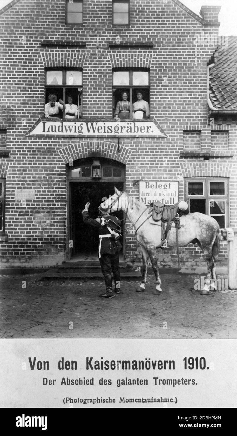 A trumpeter of the German army gallantly bids farewell to the women of the Ludwig Weisgraeber stables looking out of the windows. He sets off for the annual imperial manoeuvres, this year near Koblenz. Stock Photo