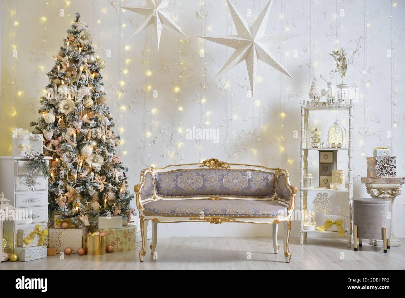 Stylish Christmas decorations in the living room with classic sofa, Christmas tree and garlands on the wall Stock Photo