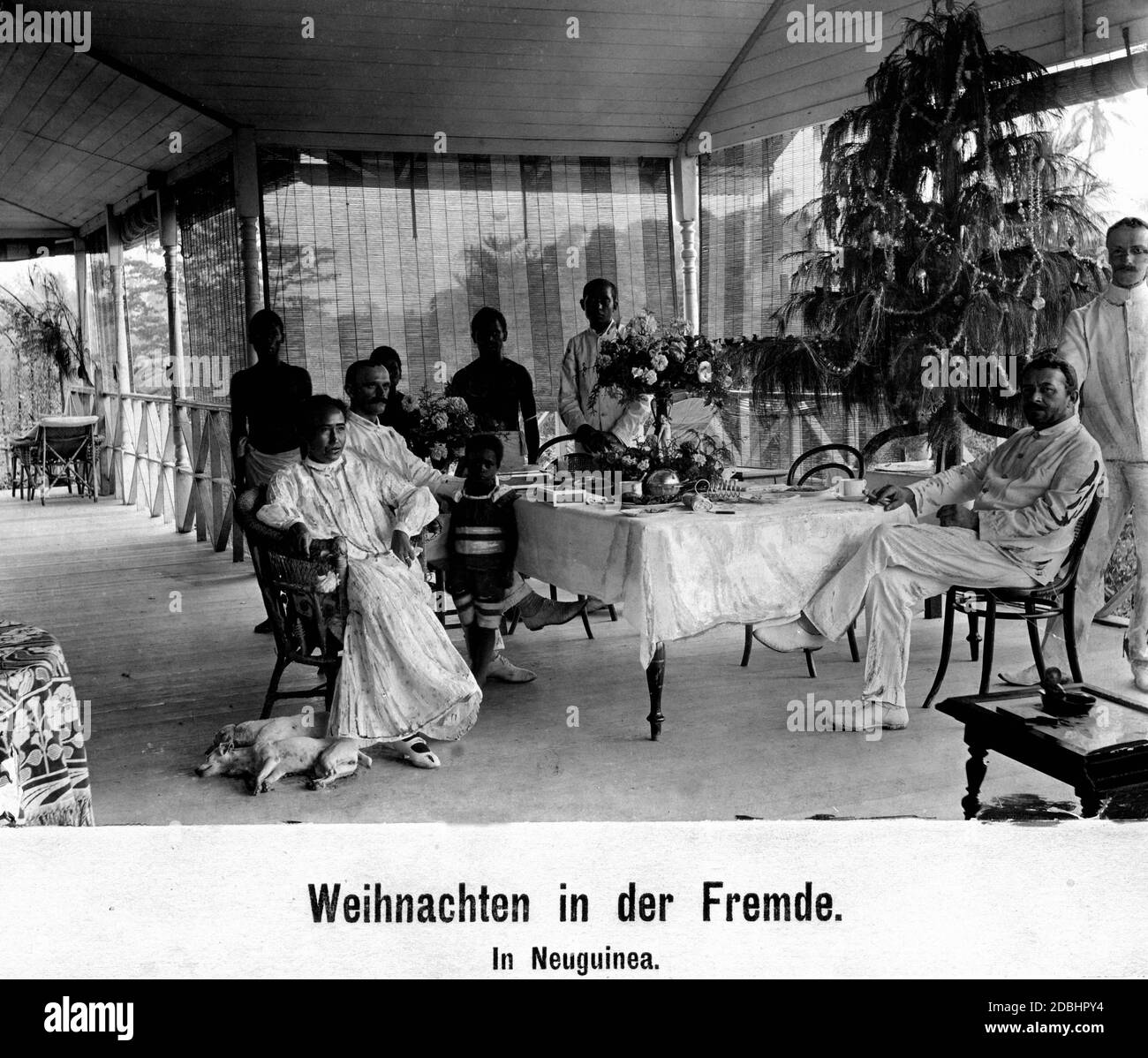 German family with local servants and a Christmas tree in their house