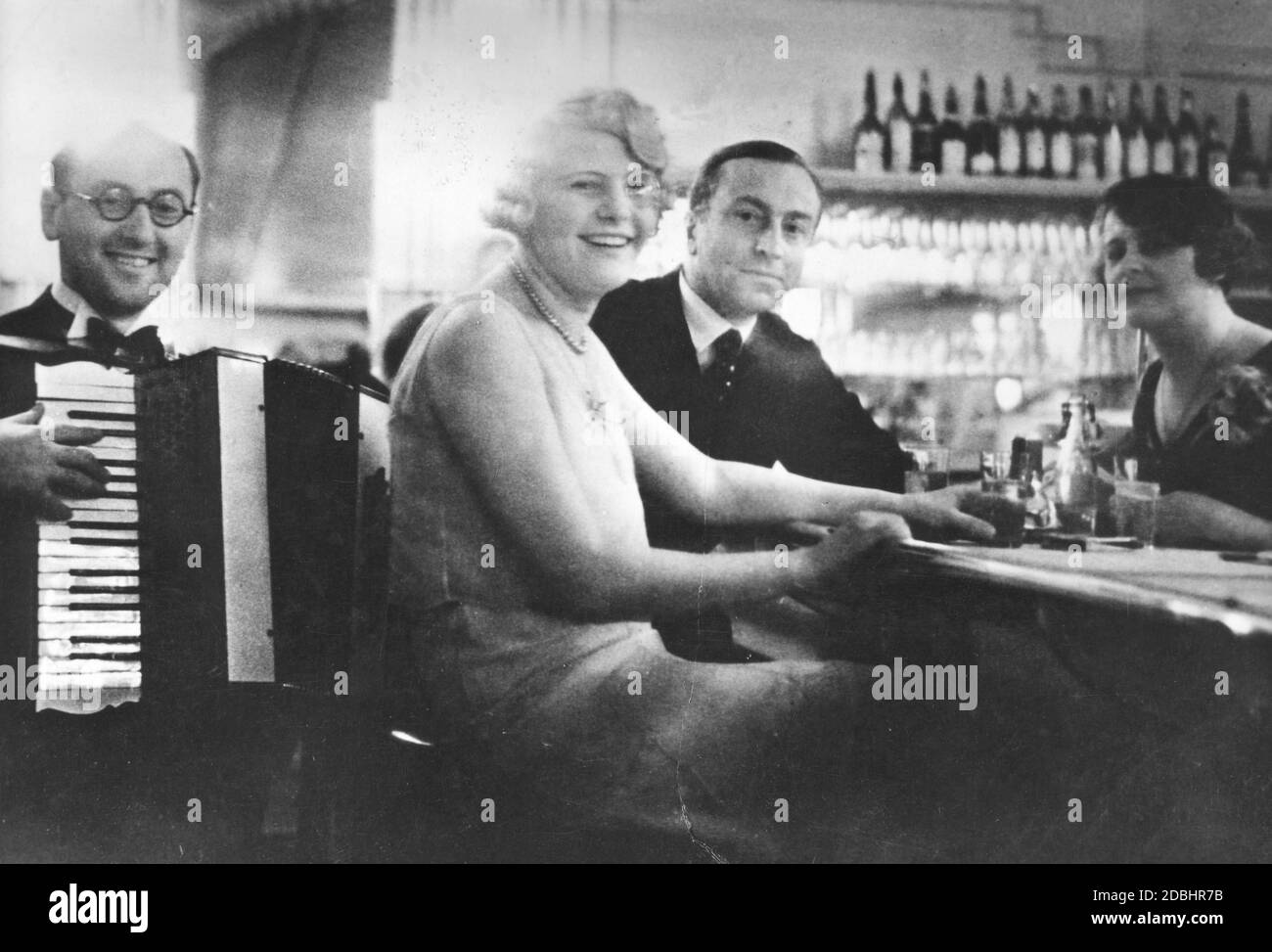 An accordion player entertains the guests sitting at the bar counter in the Femina-Palast. The photo was taken in the first years after the opening of the palace in 1931. Stock Photo