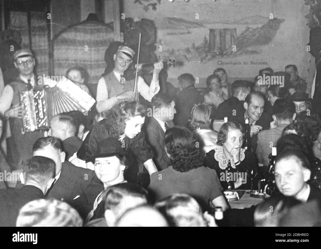 The photo is intended to demonstrate the cheerful mood of the Berlin population in October 1939 after the outbreak of war. Two musicians play for the guests of the inn. Stock Photo