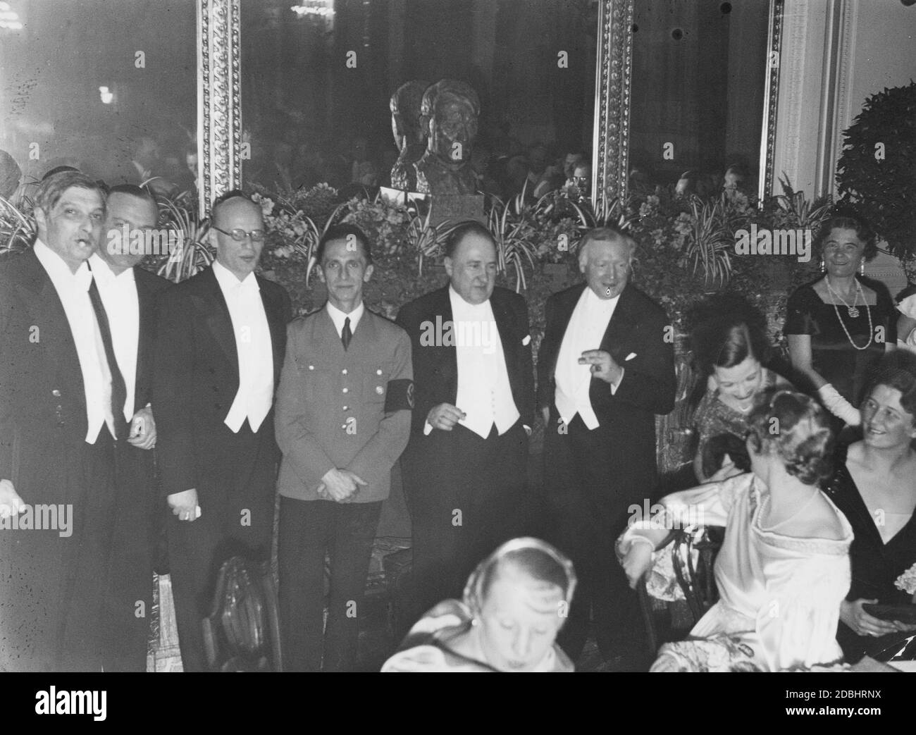 At a ball of the Prussian State Theater in the Hotel Kaiserhof in Berlin in early 1935 (from left to right): opera director Clemens Krauss, actor Paul Hartmann, actor Gustaf Gruendgens, Reich Minister Joseph Goebbels, State Secretary Walther Funk, actor Werner Krauss and his wife, the actress Maria Bard in conversation with actress Emmy Sonnemann (sitting, future wife of Hermann Goering). Stock Photo