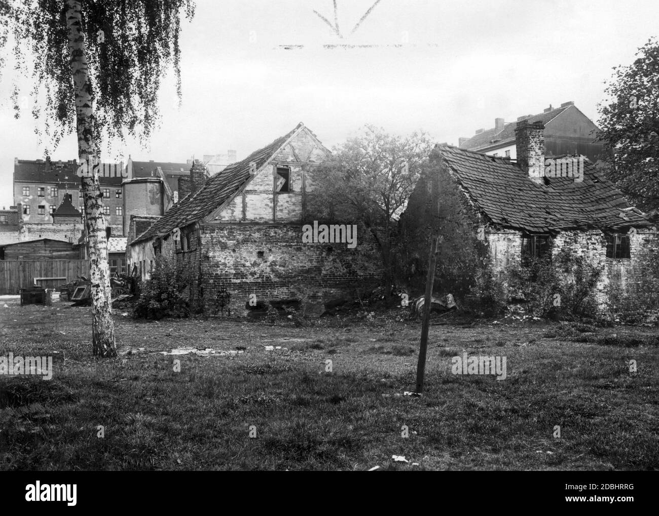 The 1932 photograph shows the rear view of a dilapidated barn and an abandoned stable of an old farm in Berlin at Muellerstrasse 16, behind which the more modern houses and tenements of the growing city already tower. Stock Photo